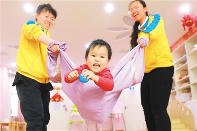今年以來，河北省張家口市橋東區紅旗樓街道聯合張垣大嫂家政服務集團開辦0.5至3歲嬰幼托育服務中心，緩解二孩三孩家庭帶娃難。圖為5月23日，紅旗樓街道紅北社區嬰幼托育服務中心育嬰師通過游戲培養孩子的身體協調能力。岑屹攝（人民視覺）