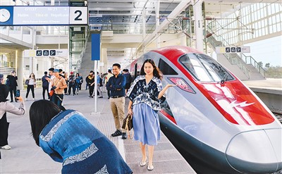 中印尼共建“一带一路”合作的标志性项目——雅万高铁于10月17日正式开通运营。图为当日印度尼西亚万隆德卡鲁尔站，乘客在站台上和雅万高铁高速动车组列车合影。  新华社记者 徐 钦摄