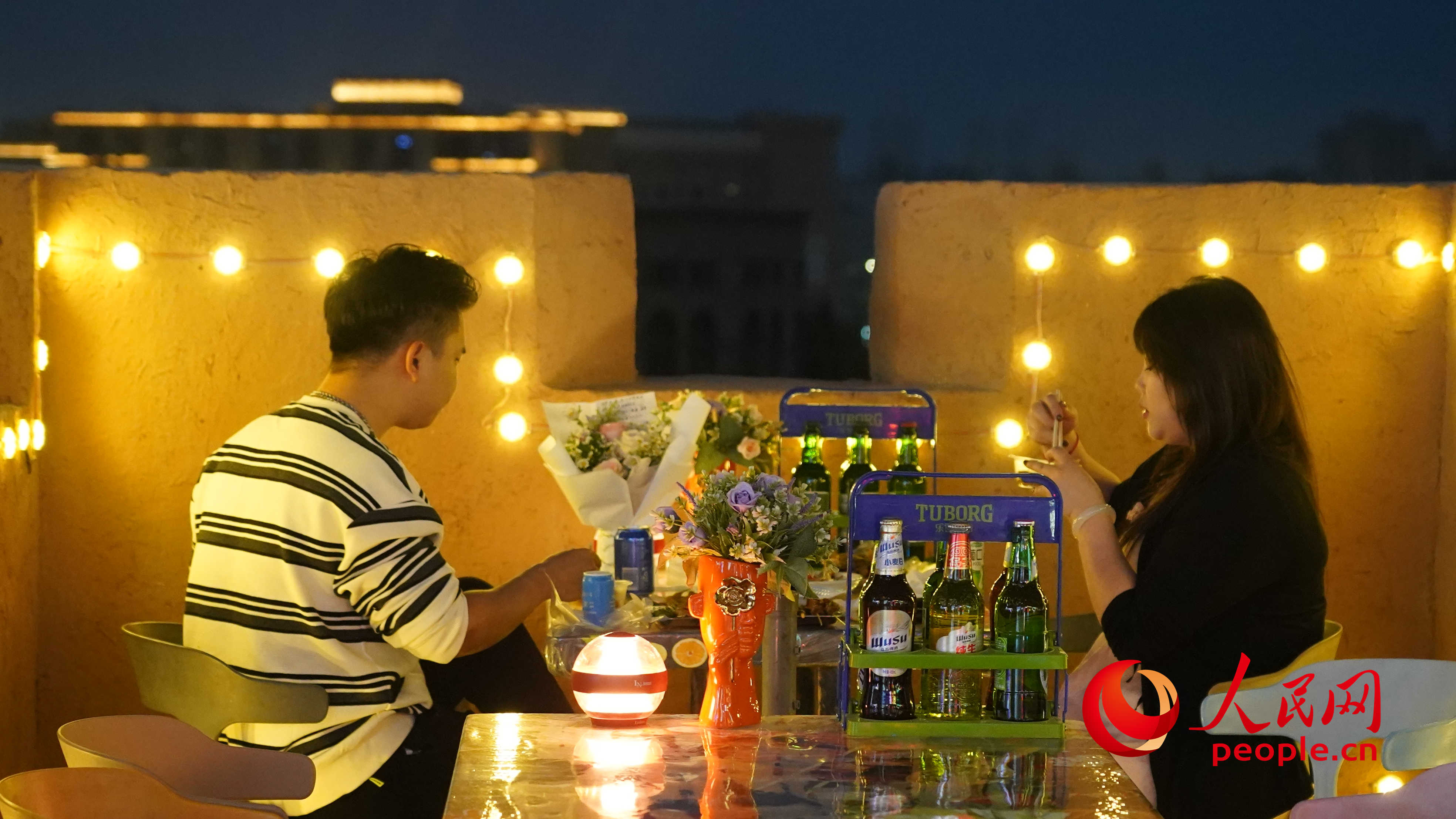 夜晚的古城燈火璀璨，一對情侶正在享用美食。人民網(wǎng) 李龍攝