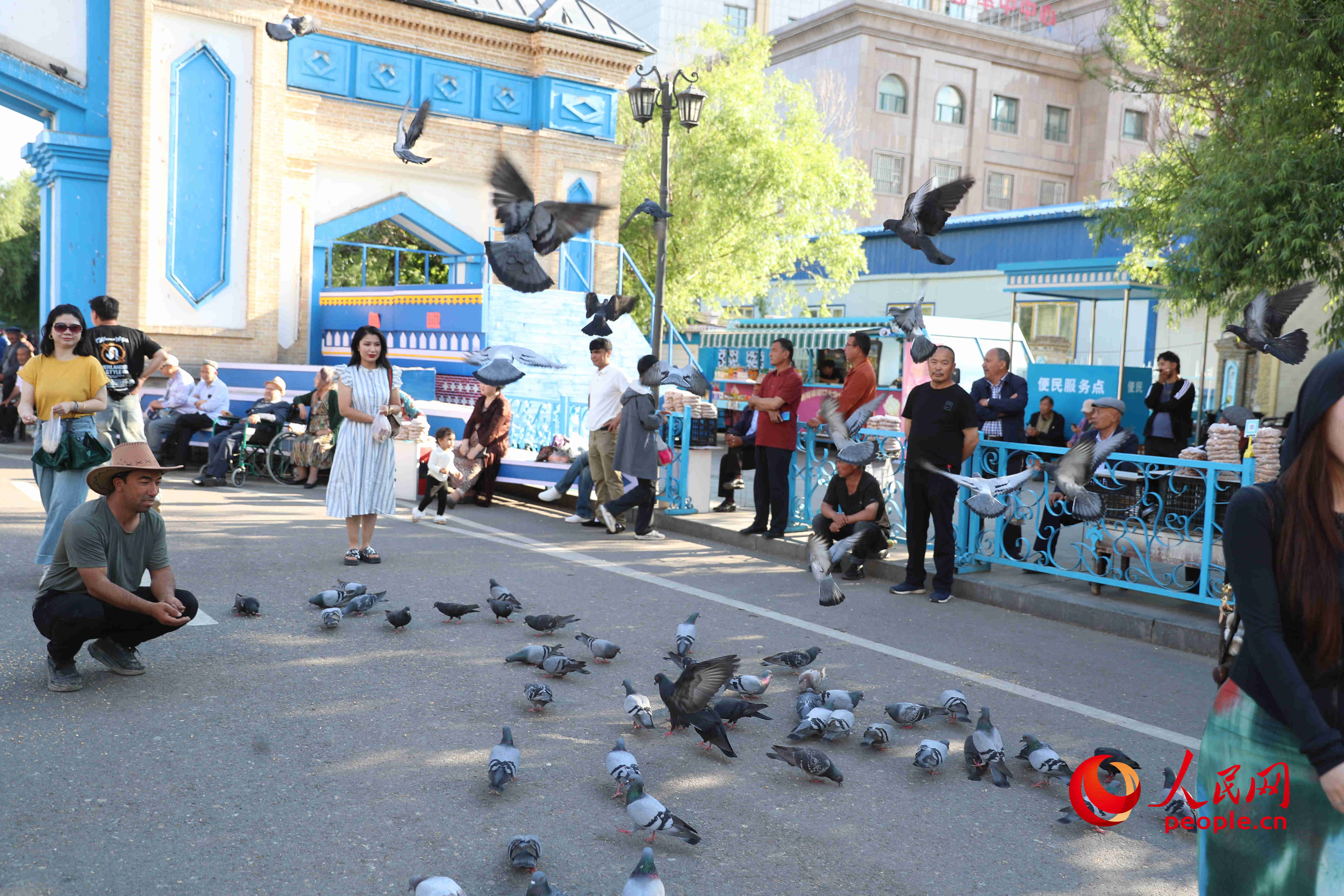 景區(qū)大門口，游客和市民正在喂鴿子。人民網(wǎng) 李龍攝
