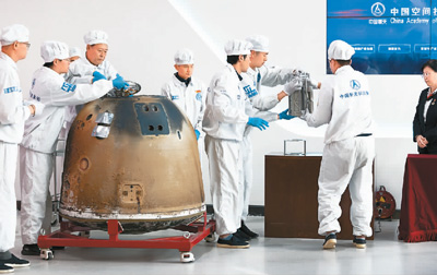 在中国航天科技集团五院举行的嫦娥六号返回器开舱仪式现场,科研人员取出月球样品容器准备称重。 新华社记者 金立旺摄 在中国航天科技集团五院举行的嫦娥六号返回器开舱仪式现场,科研人员取出月球样品容器准备称重。 新华社记者 金立旺摄