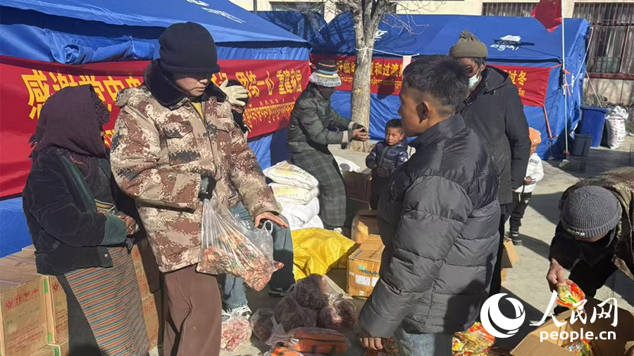 90后鄉(xiāng)村振興專干格桑卓瑪（左二）給受災群眾發(fā)放物資。人民日報記者 瓊達卓嘎攝