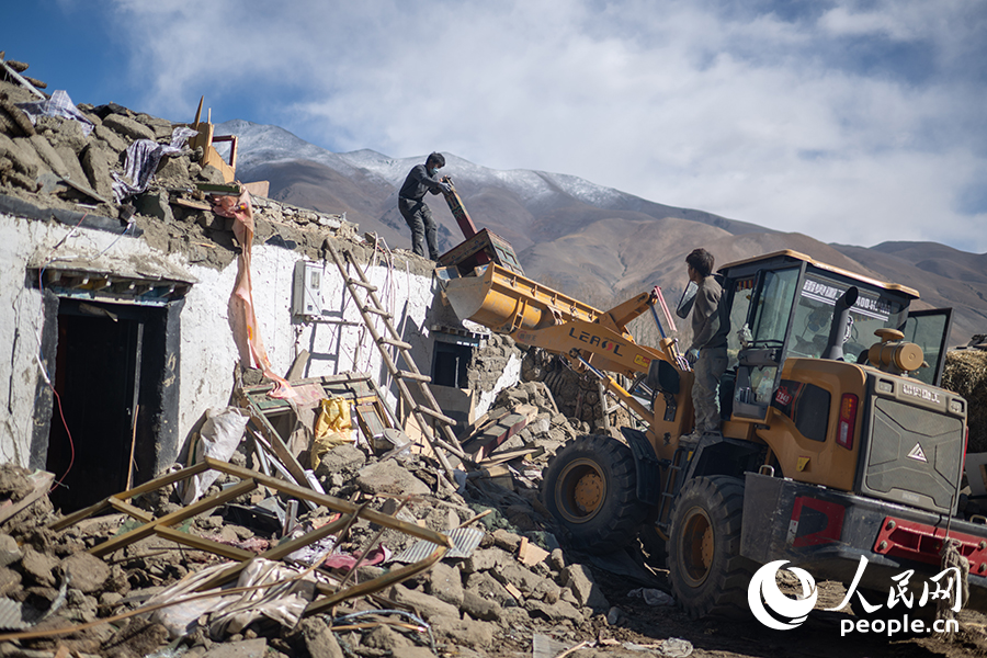 1月13日，長所鄉(xiāng)嘎旦村村書記吳堅加布（左）正在村中清理廢墟。人民網(wǎng)記者 翁奇羽攝