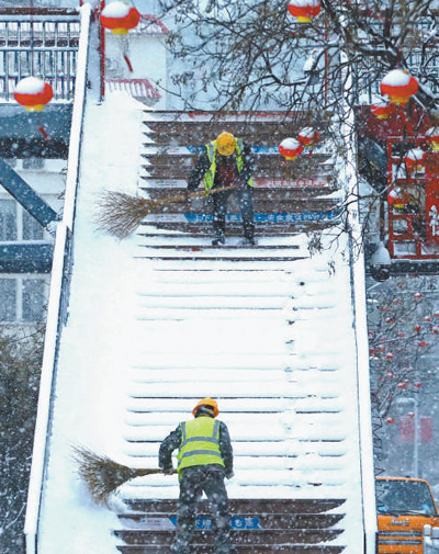 山东威海市环翠区，市政工人在清扫过街天桥积雪。刘中华摄（新华社发）